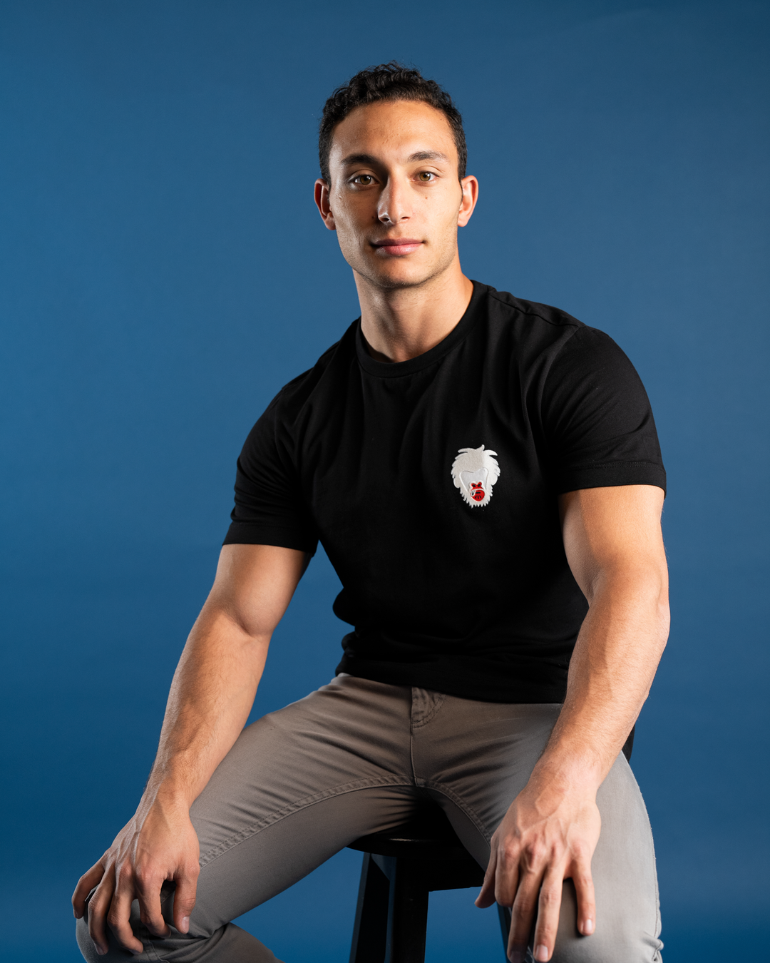 Man wearing a black t-shirt with a Master Monkey logo against a blue background #color_black