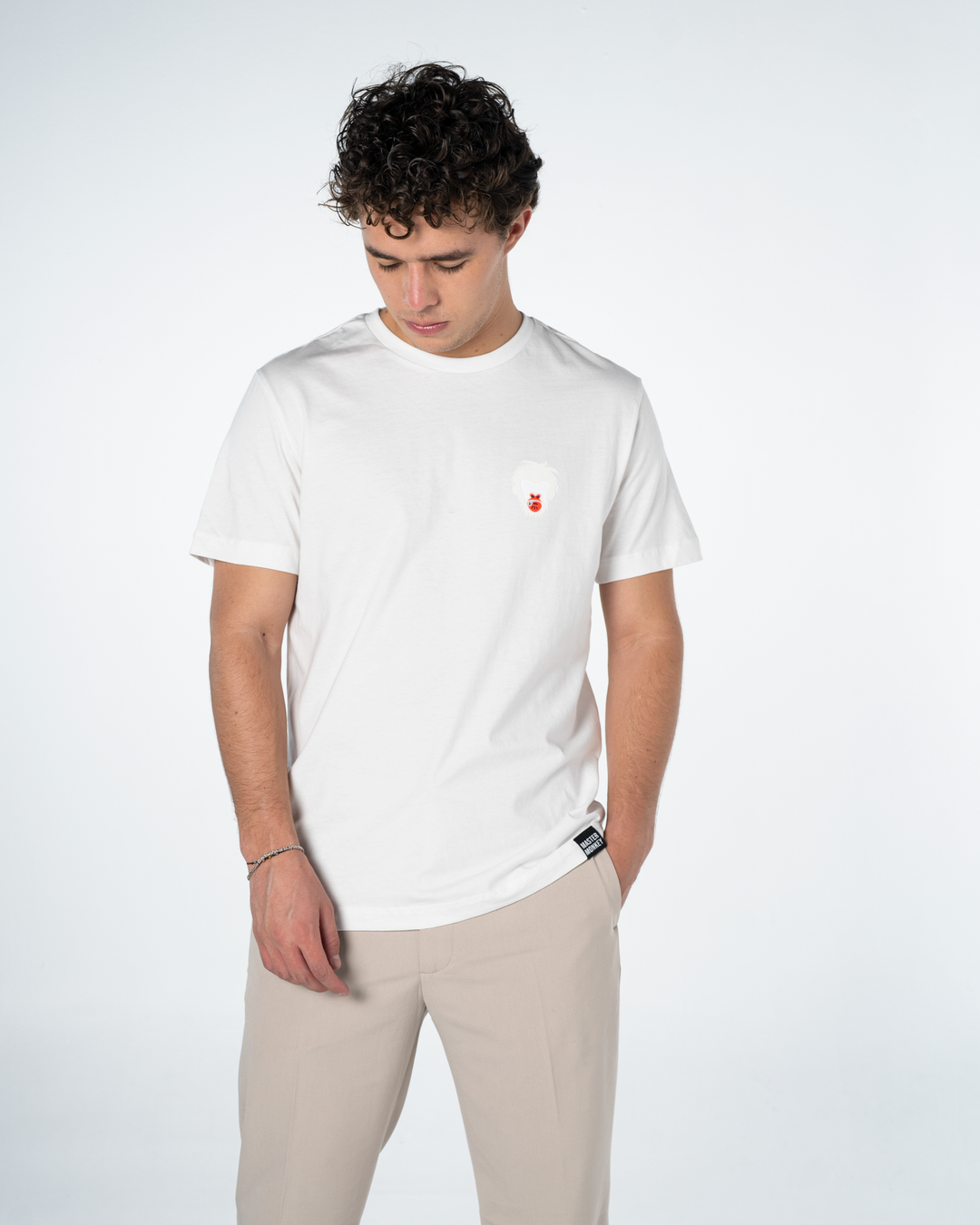 Man wearing a white t-shirt with a small Master monkey logo on a plain background #color_white