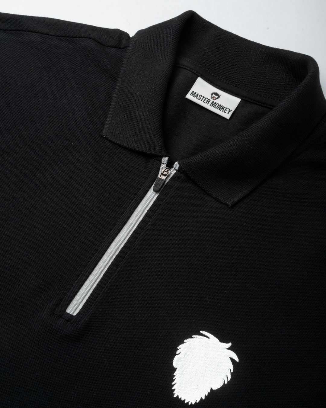 Black polo shirt with a reflective logo and zipper detail on a white background #color_black