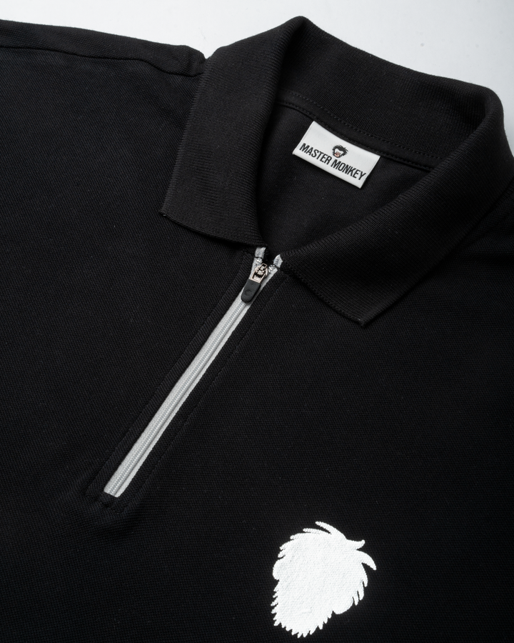 Black polo shirt with a reflective logo and zipper detail on a white background #color_black