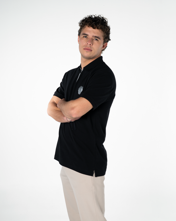 Man wearing a black polo shirt with a logo on a white background #color_black