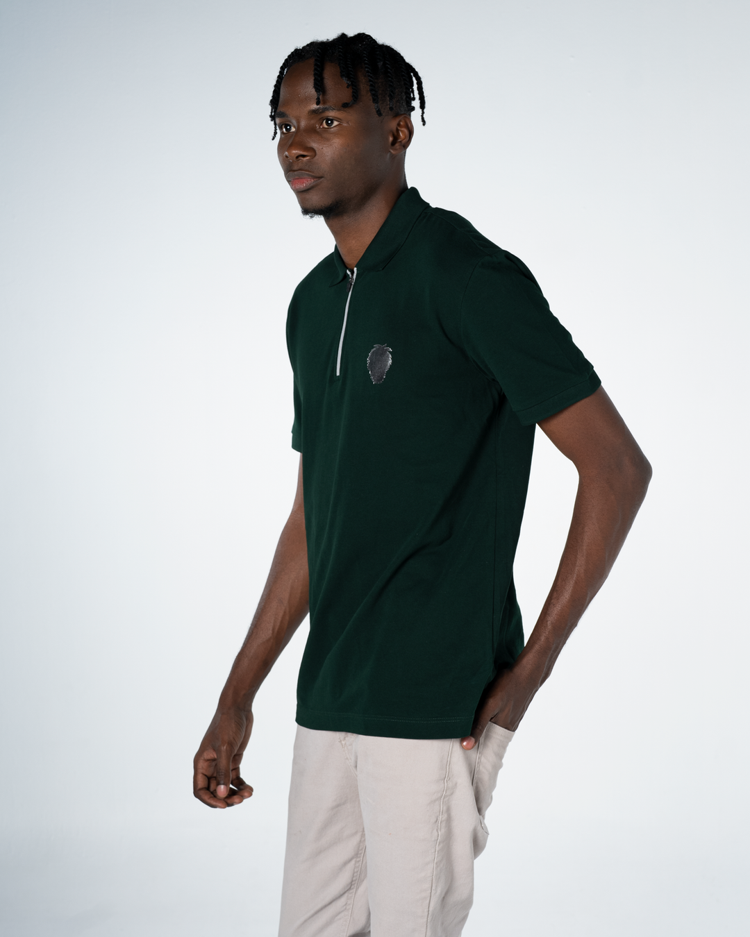 Man wearing a dark green polo shirt with a logo on a white background #color_gunmetal-green