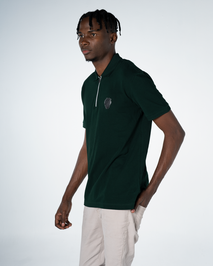 Man wearing a dark green polo shirt with a logo on a white background #color_gunmetal-green