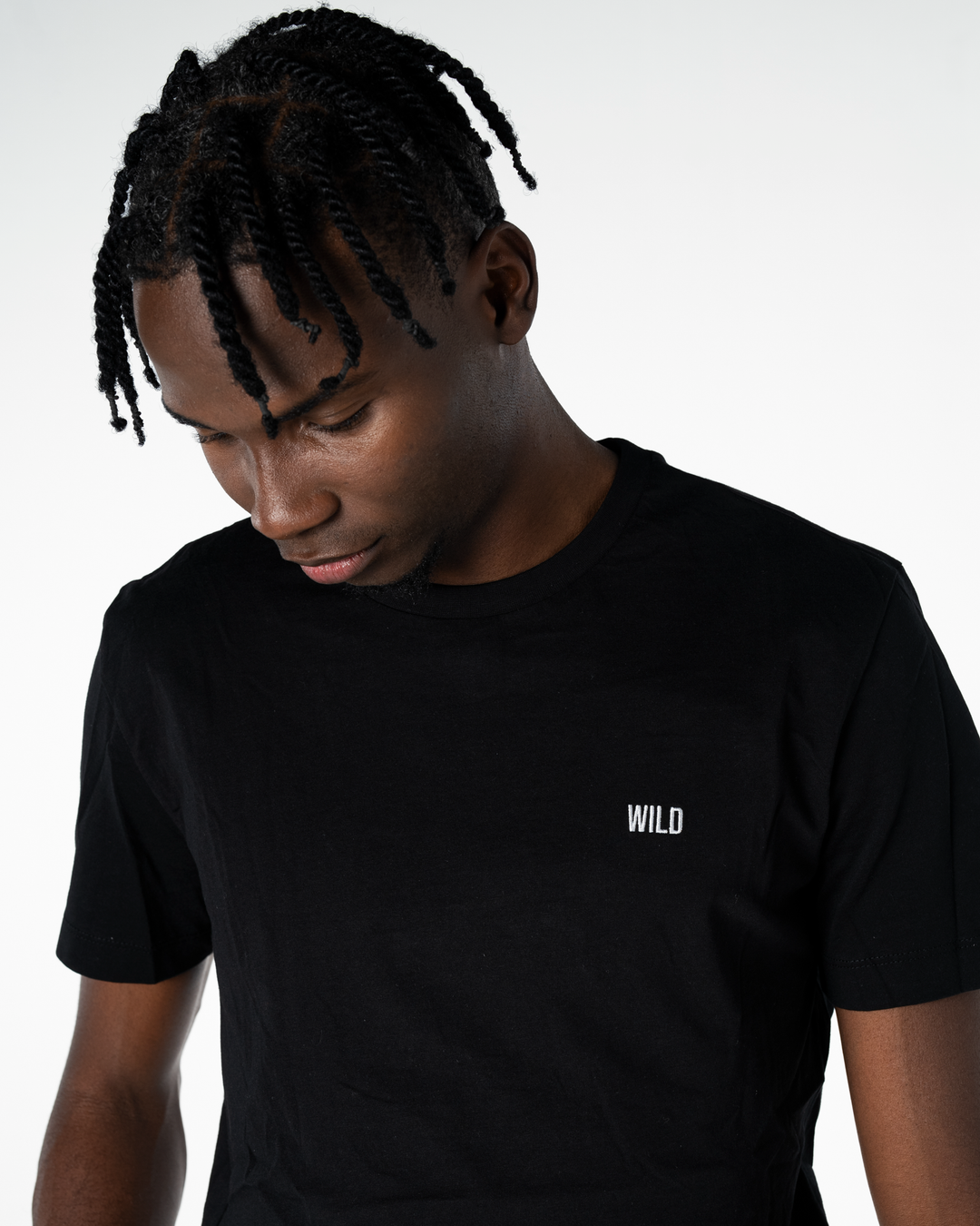 Person wearing a black t-shirt with 'WILD' logo on a white background #color_black
