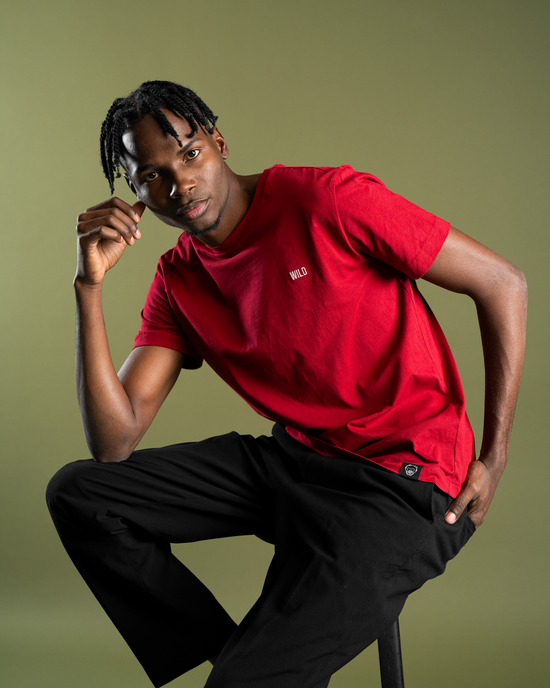 Person wearing a red t-shirt with a logo on a green background #color_brick