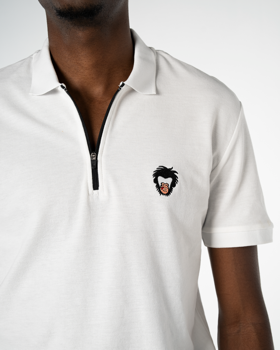 Close up on the Master Monkey standard issue polo in white, with a zipper front color and embroidered logo #color_white