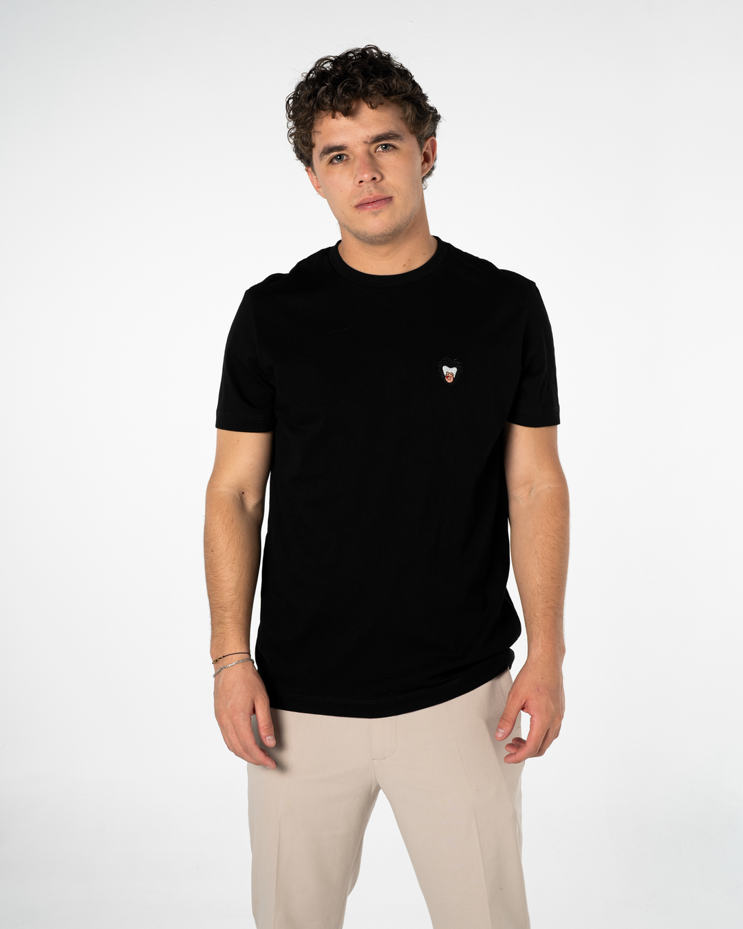 Man wearing a black t-shirt with a small logo on a white background #color_black