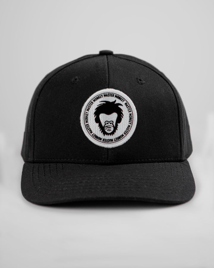 Black cap with a white logo featuring a bearded face on a light gray background #color_black