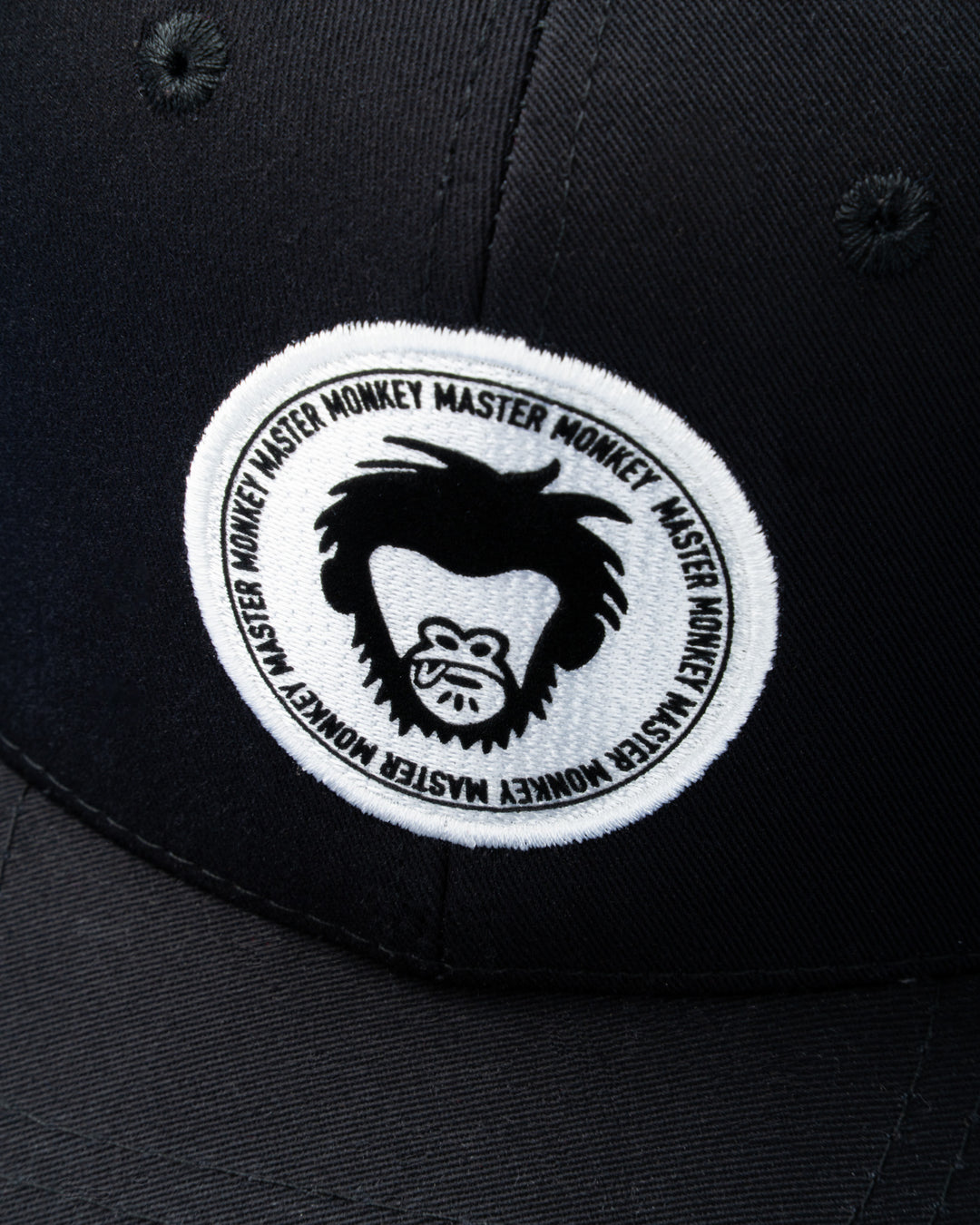 Black cap with a white embroidered patch featuring a logo and text on a dark background #color_black